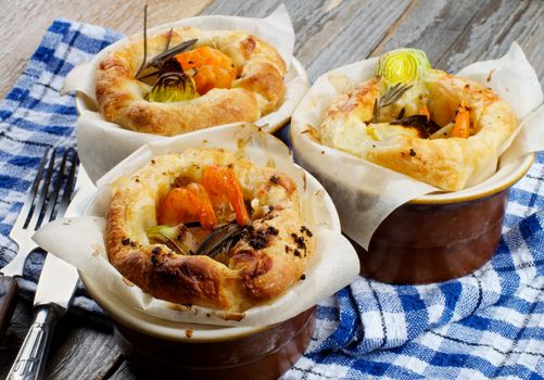 Delicious Puff Pastry Snacks with Shrimps, Leek and Cheese Oven-Baked in Ramekin with Fork, Knife and Napkin closeup on Wooden background