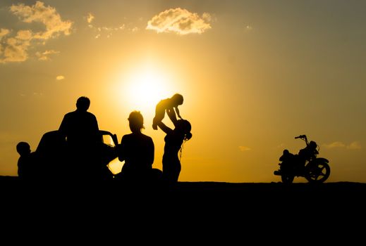 happy family of three people,celebrate outside at Sunset, Silhouette against the evening sky