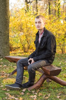 young attractive man in a black jacket in autumn park