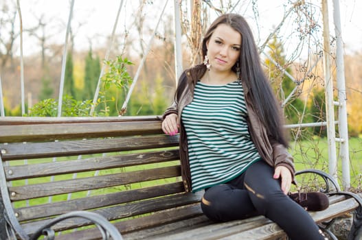 beautiful and sexy girl sitting on bench outdoors. 