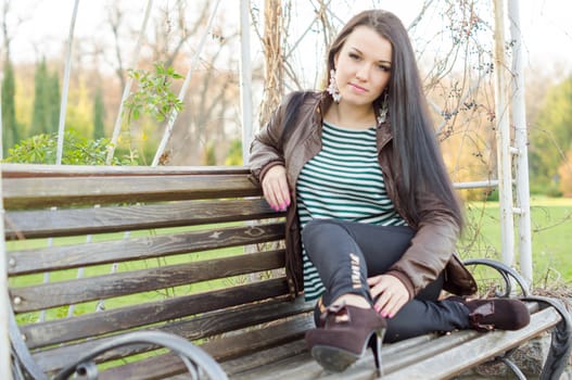 beautiful and sexy girl sitting on bench outdoors. 