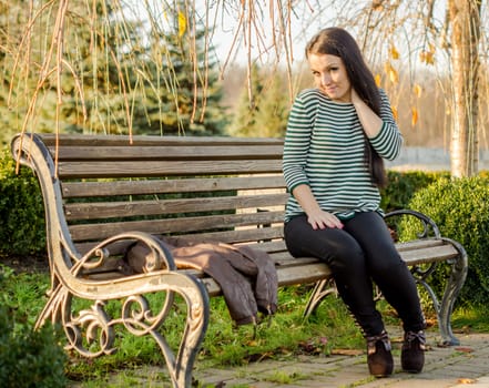 beautiful and sexy girl sitting on bench outdoors. 