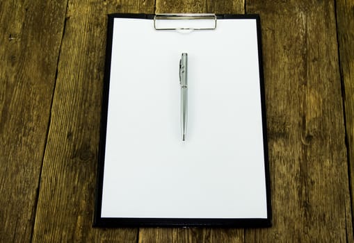 White paper and pen on wood background. For your commercial and editorial use