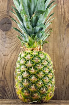 Ripe tasty pineapple lie on a wooden background.