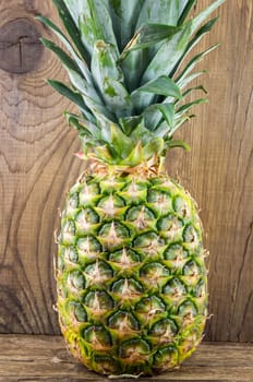Ripe tasty pineapple lie on a wooden background.