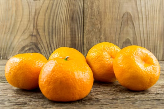 Ripe tangerines lie on a wooden background