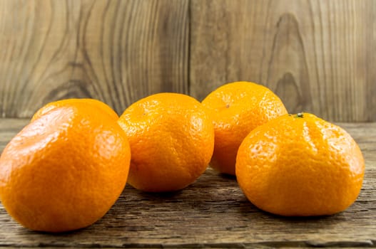 Ripe tangerines lie on a wooden background