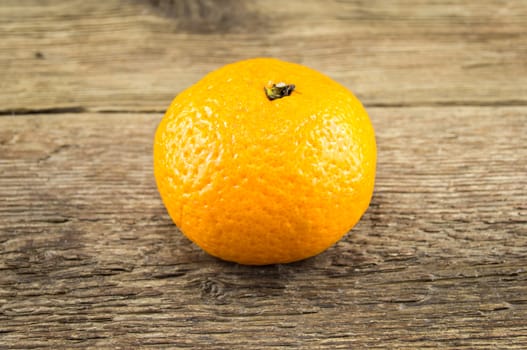 Ripe tangerines lie on a wooden background.