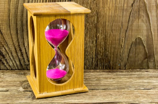 Hourglass with space for text on the wooden background.