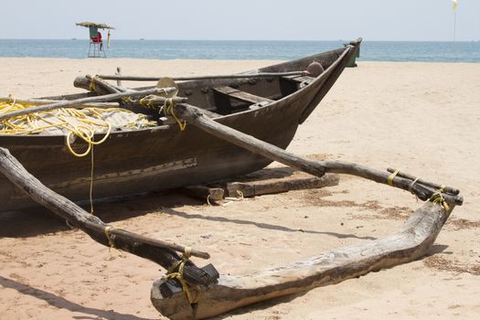 Old fishing boat standing on the sandy beach. India, Goa.