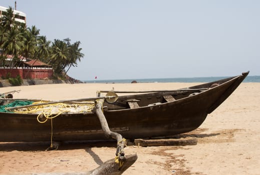 Old fishing boat standing on the sandy beach. India, Goa.