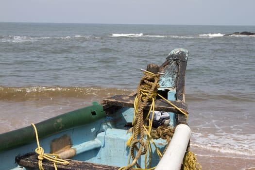 Old fishing boat standing on the sandy beach. India, Goa.