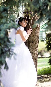 Happy Bride smiling near summer tree outdoors. For your commercial and editorial use.