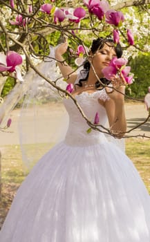 Young happy bride smells flowers magnolia outdoors. For your commercial and editorial use.