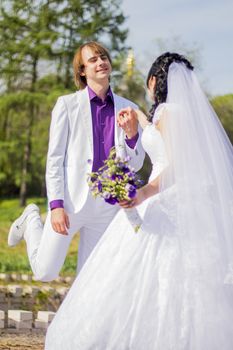 Newly married couple dancing in field. Outdoor portrait of bride and groom