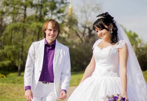 Beautiful bride and groom newlywed couple with bouquet flowers at bridal day embracing together. Happy Woman in wedding dress and man in love. Romantic Relationship. Smiling wife and husband