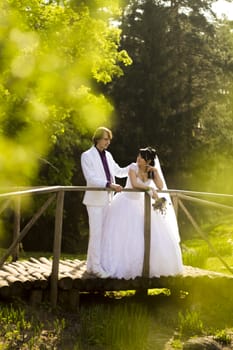 Happy bride and groom on a wooden bridge in the park at the wedding walk