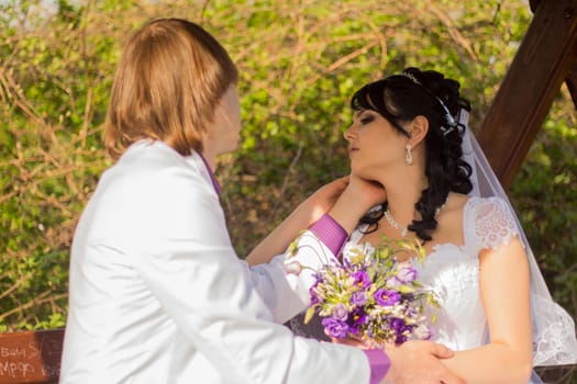 Romantic wedding couple sitting on a bench in the park.