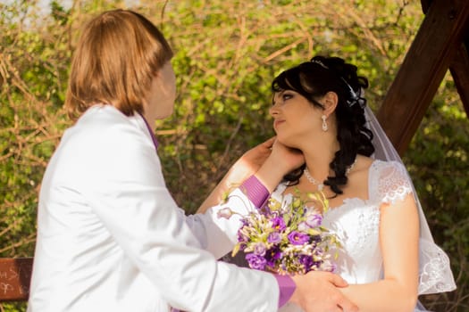 Romantic wedding couple sitting on a bench in the park.