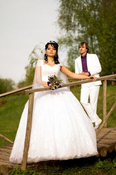 Happy just married couple standing on the small bridge.