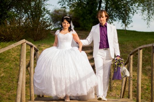 Happy just married couple standing on the small bridge.