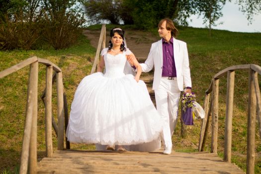 Happy just married couple standing on the small bridge.