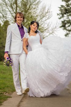 Happy bride and groom in shady alley on wedding walk