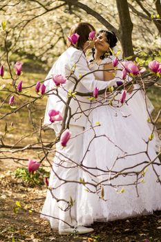 Newlyweds on nature background with blossoming magnolias.