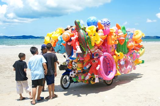 RAYONG,THAILAND-MAY 07,2015 :The man ride mobile shop selling toys to child  on the beach in Eastern Thailand.