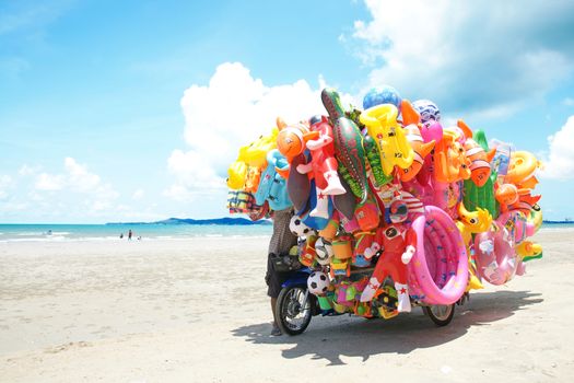 RAYONG,THAILAND-MAY 07,2015 :The man ride mobile shop selling toys to child  on the beach in Eastern Thailand.