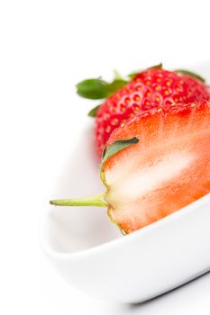 Closeup of the juicy flesh of a halved fresh ripe strawberry in a white ceramic bowl for use in cooking and baking as a healthy ingredient rich in vitamin C