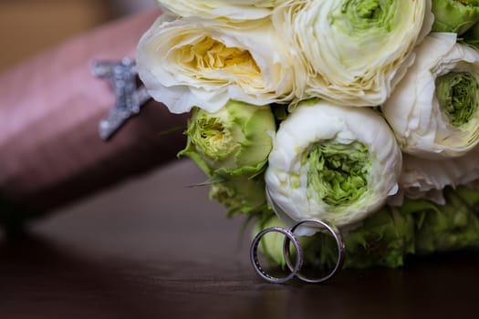 Bouquet of white roses and silver wedding rings