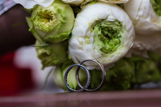 Bouquet of white roses and silver wedding rings