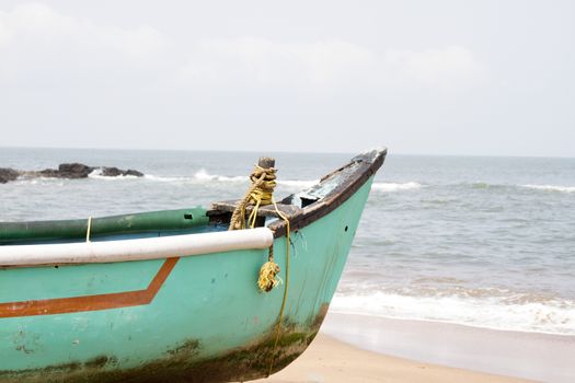 Old fishing boat standing on the sandy beach. India, Goa.