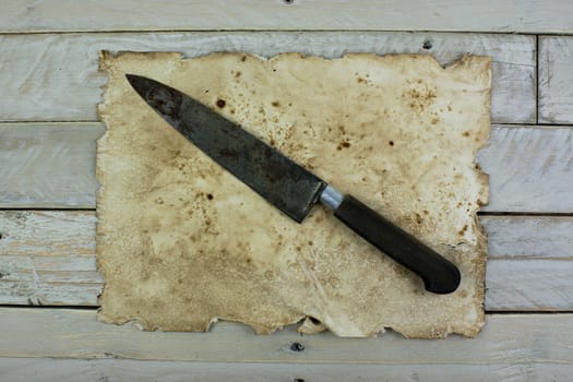 Piece of old paper and a knife on wooden planks