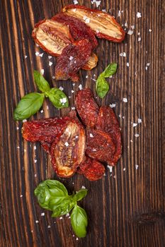 Delicious dried tomatoes on brown wooden vintage textured background. Traditional mediterranean kitchen.