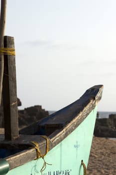 Old fishing boat standing on the sandy beach. India, Goa.