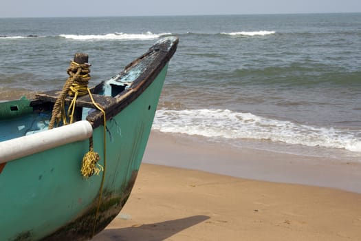 Old fishing boat standing on the sandy beach. India, Goa.