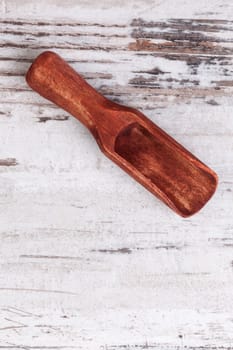 Wooden scoop on white textured wooden background with copy space. Gastronomy background. 