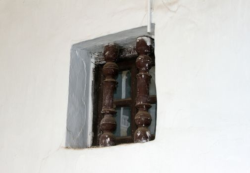 Old window with a lattice on a white wall.