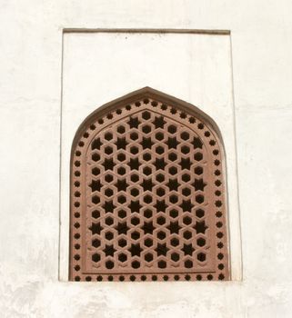 Old window with a lattice on a white wall.