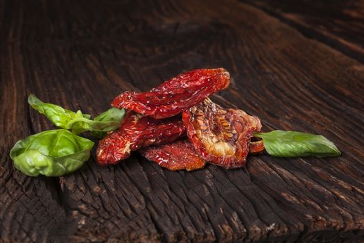 Delicious dried tomatoes on brown wooden vintage textured background. Traditional mediterranean kitchen.