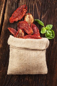 Delicious dried tomatoes on brown wooden vintage textured background. Traditional mediterranean kitchen.