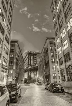 The Manhattan Bridge framed at night by Brooklyn buildings.