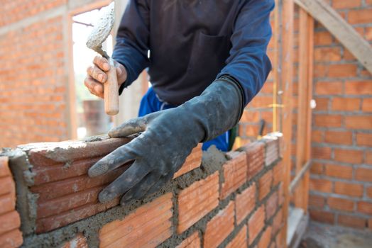 Worker building masonry house wall with bricks 