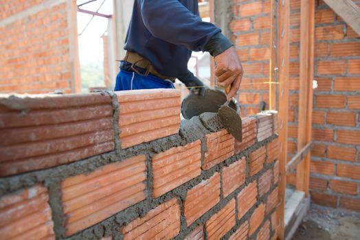 Worker building masonry house wall with bricks 