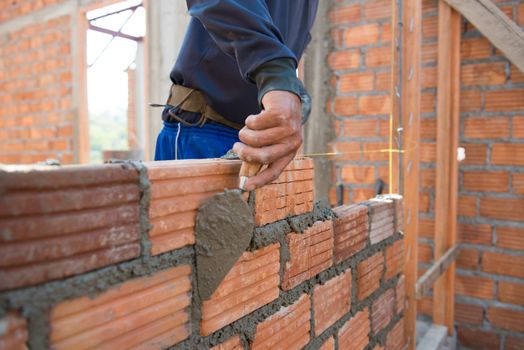 Worker building masonry house wall with bricks 