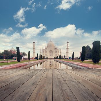 A perspective view from wooden balcony to Taj Mahal mausoleum with reflection in water.