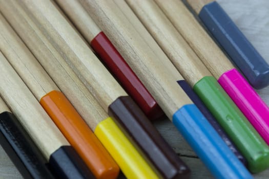 Close f of coloured pencils against a wooden background