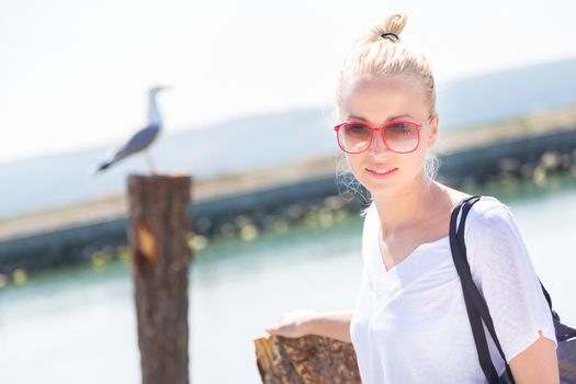 Portrait of a stylish lady strolling on the beach. Summertime feeling.